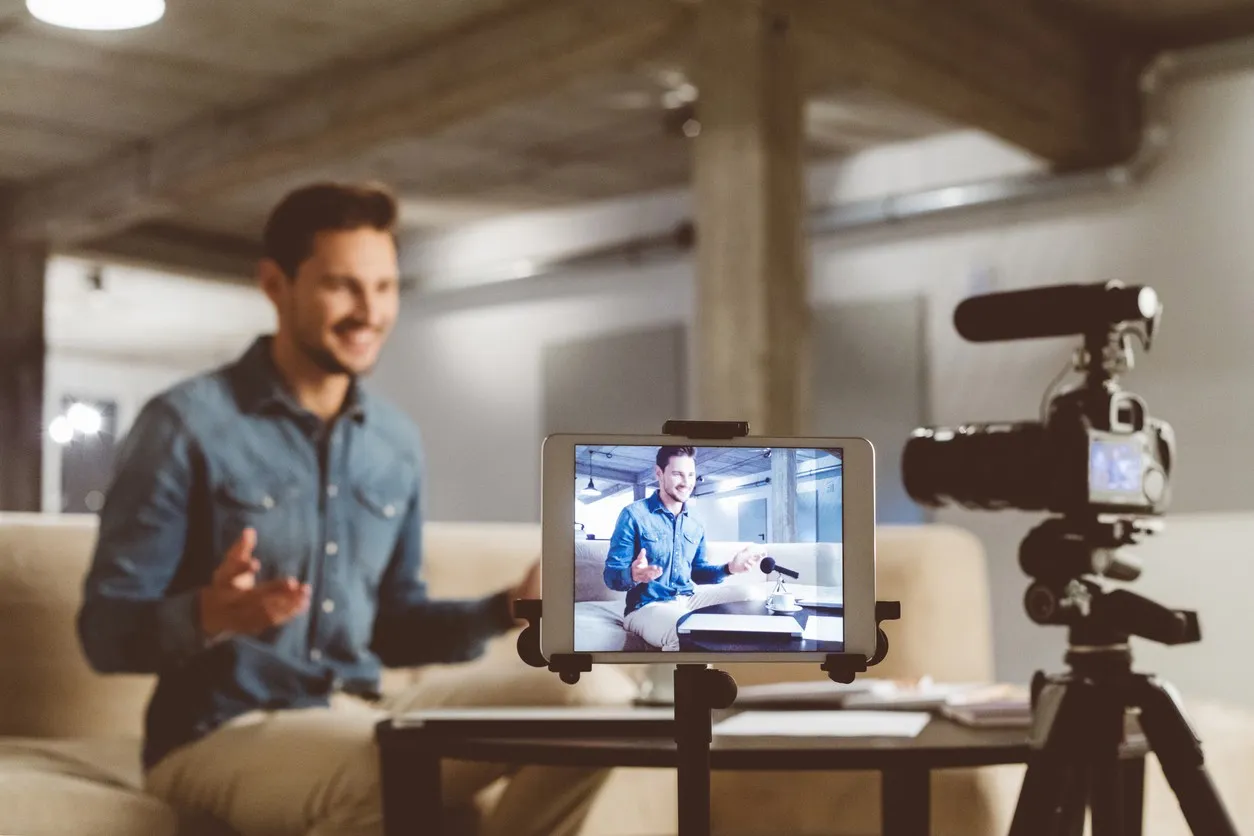 Man filming himself with a camera and a tablet on a tripod